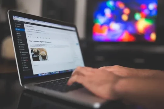 A person typing on a laptop in WordPress while writing a blog post