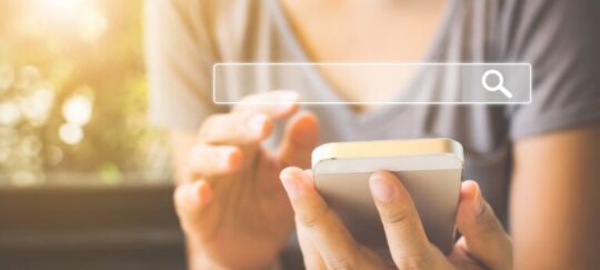 A person using a smartphone with a search bar graphic on the screen.