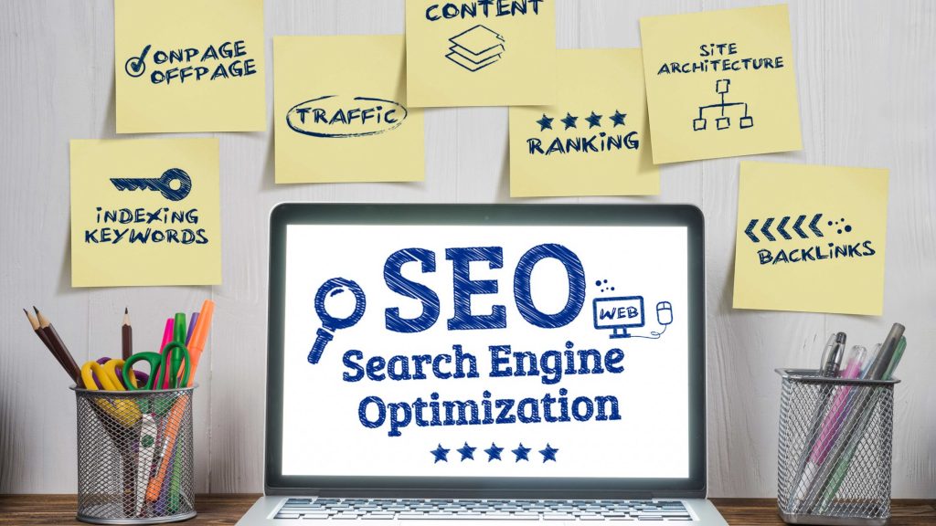 SEO written on a laptop, with different terms on sticky notes