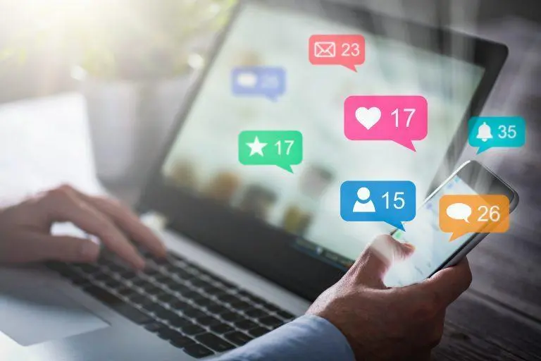 icons of likes, shares, comments over a laptop screen
