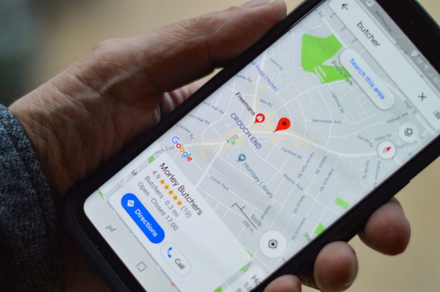zoomed in view of a hand holding phone with mobile optimized view of a local shop