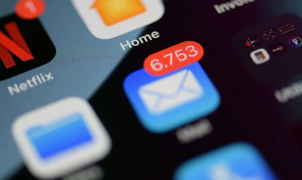 A close-up of a smartphone showing the email app with 6,753 unread messages.
