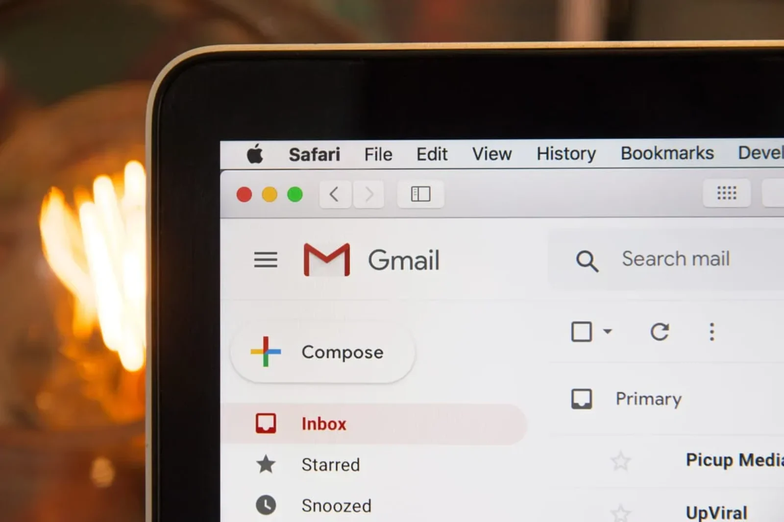A close-up view of a Gmail inbox on a laptop screen showing various email folders like Inbox, Starred, and Snoozed.