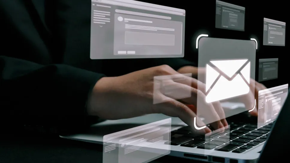 A person typing on a laptop with floating digital email icons, symbolizing email marketing tools and automation.