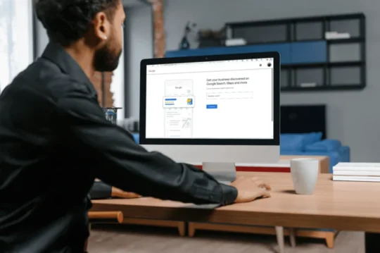 A person sitting at a desk using a desktop computer displaying a Google Business Profile setup page.