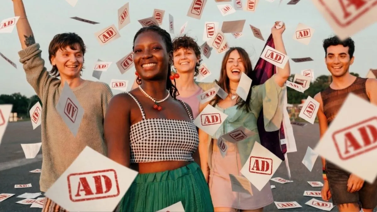 Group of young people celebrating outdoors with “AD” cards flying around them in the air.
