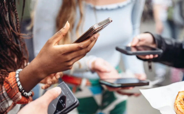 Multiple people holding smartphones in a group setting.