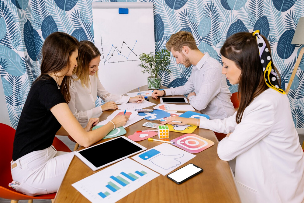Team collaborating on a social media marketing strategy around a table with charts and devices.