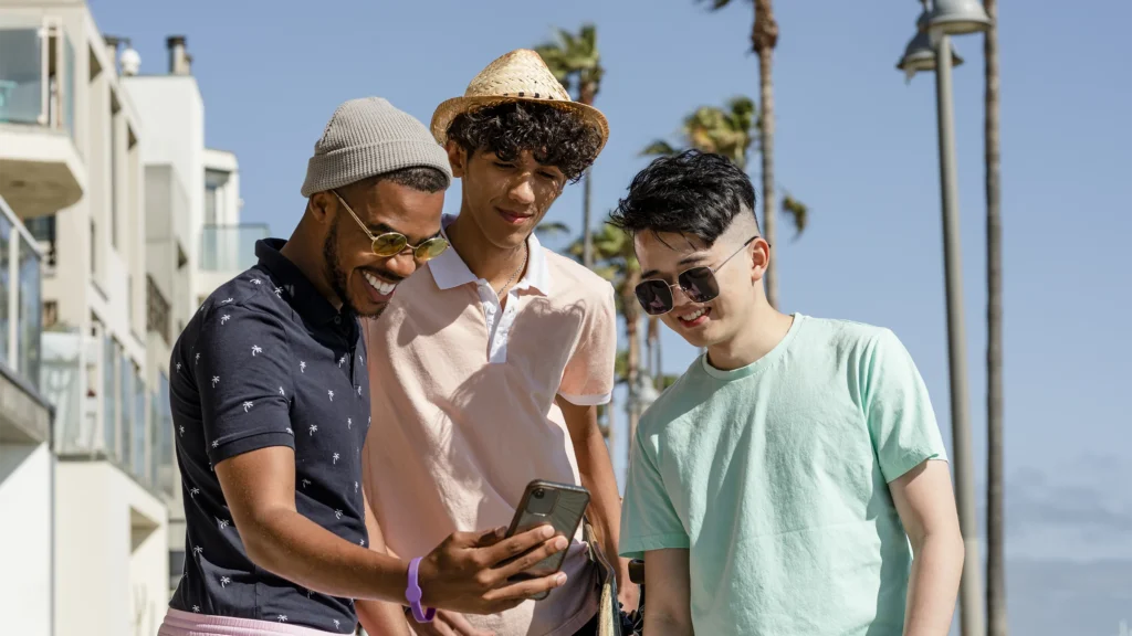Three friends outdoors looking at a smartphone together.