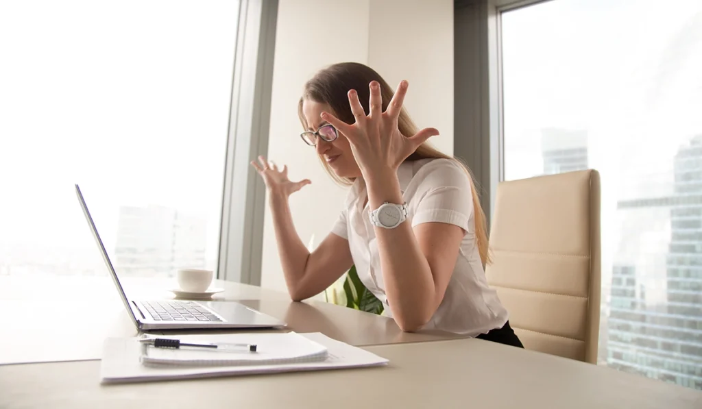 Woman frustrated at laptop in an office reacting to slow website performance and also knows how important is page speed