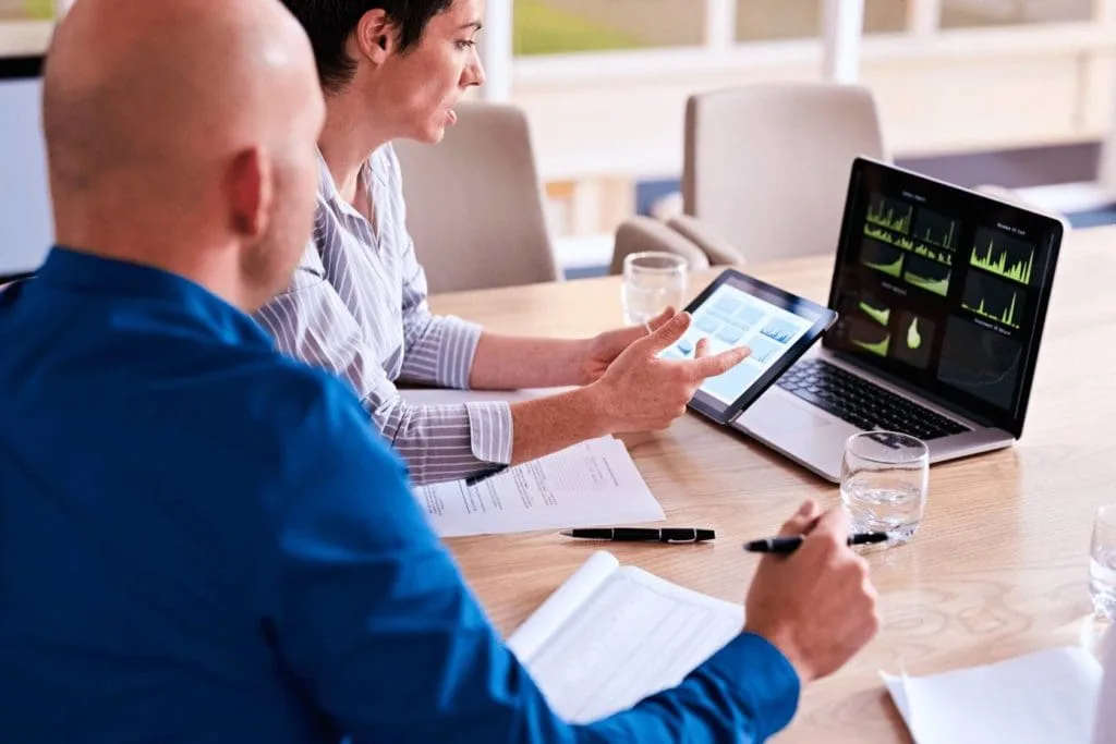 experts discussing KPIS on laptop and tablet in a corporate setting