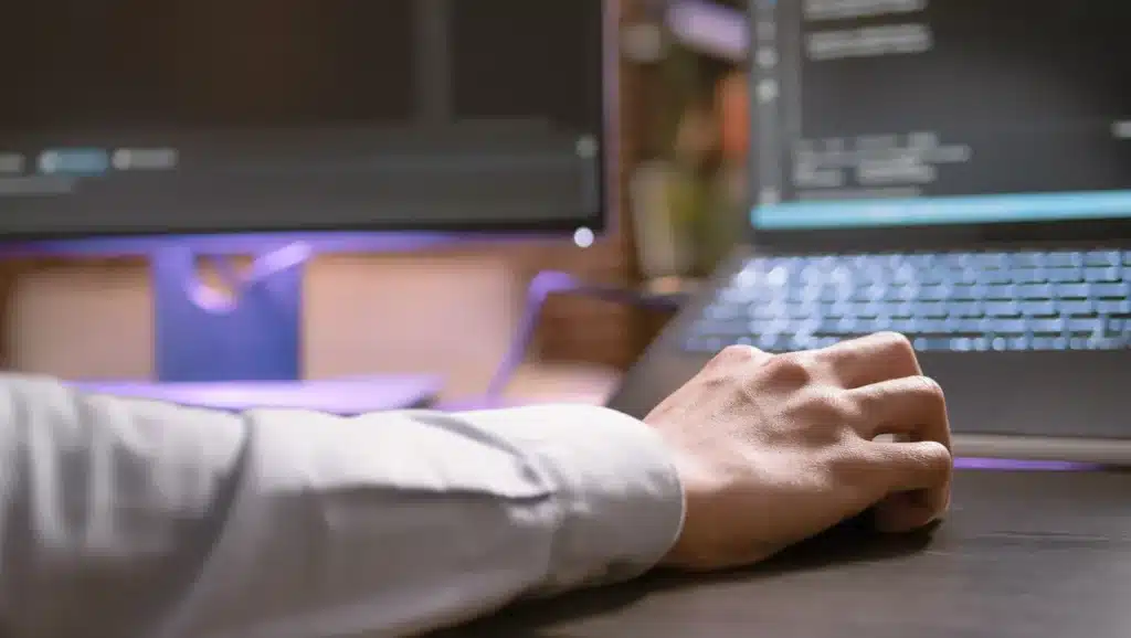 Developer working on code and software development tasks using a laptop and computer screens.