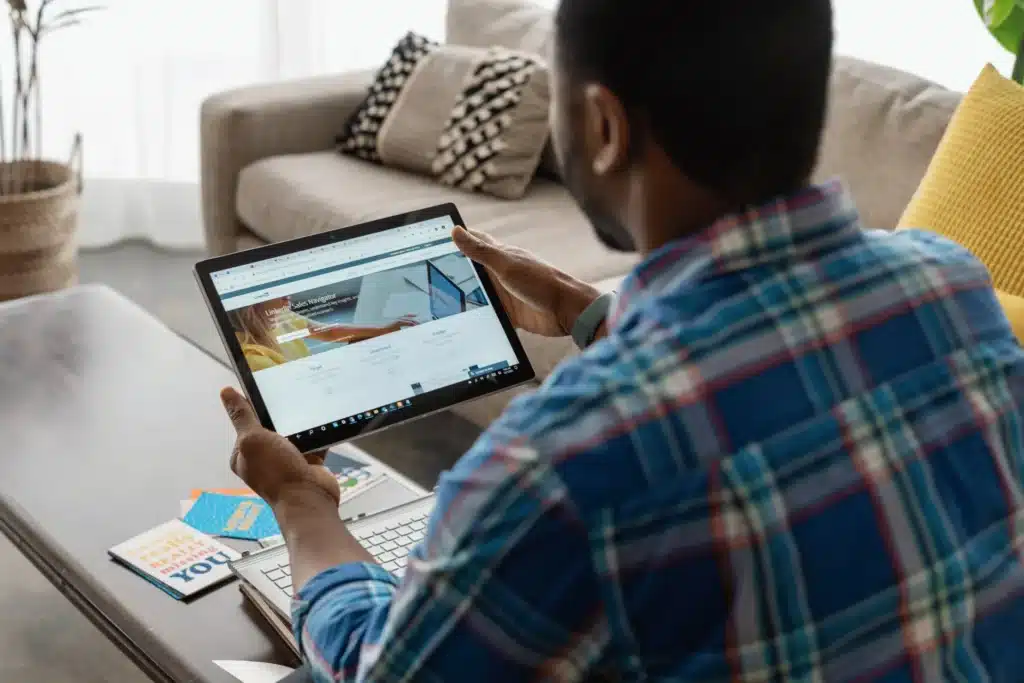 Person using a tablet to access LinkedIn, showing a professional networking platform on screen.